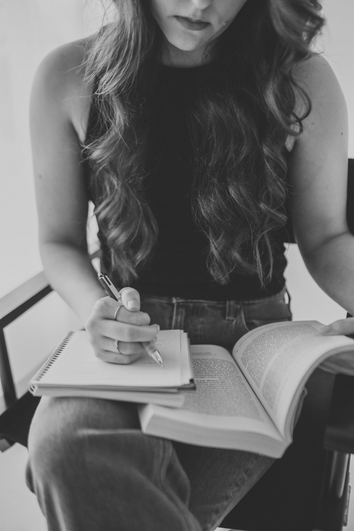 Jordyn, founder of Oleander Copy Studio, looking at an open book in one hand and writing in a notebook in the other
